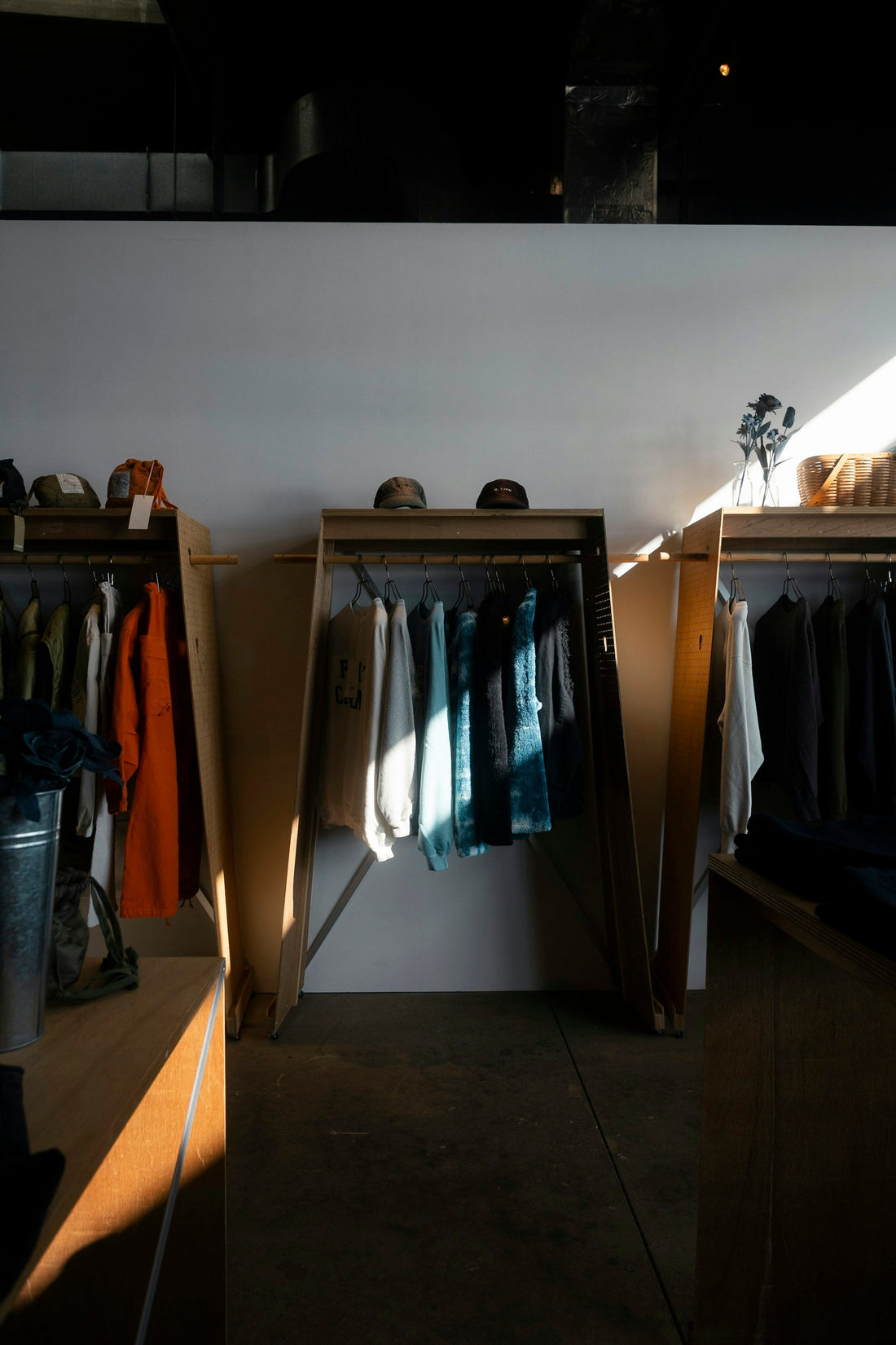 A clothing shop interior with different garments on rails caught by daylight