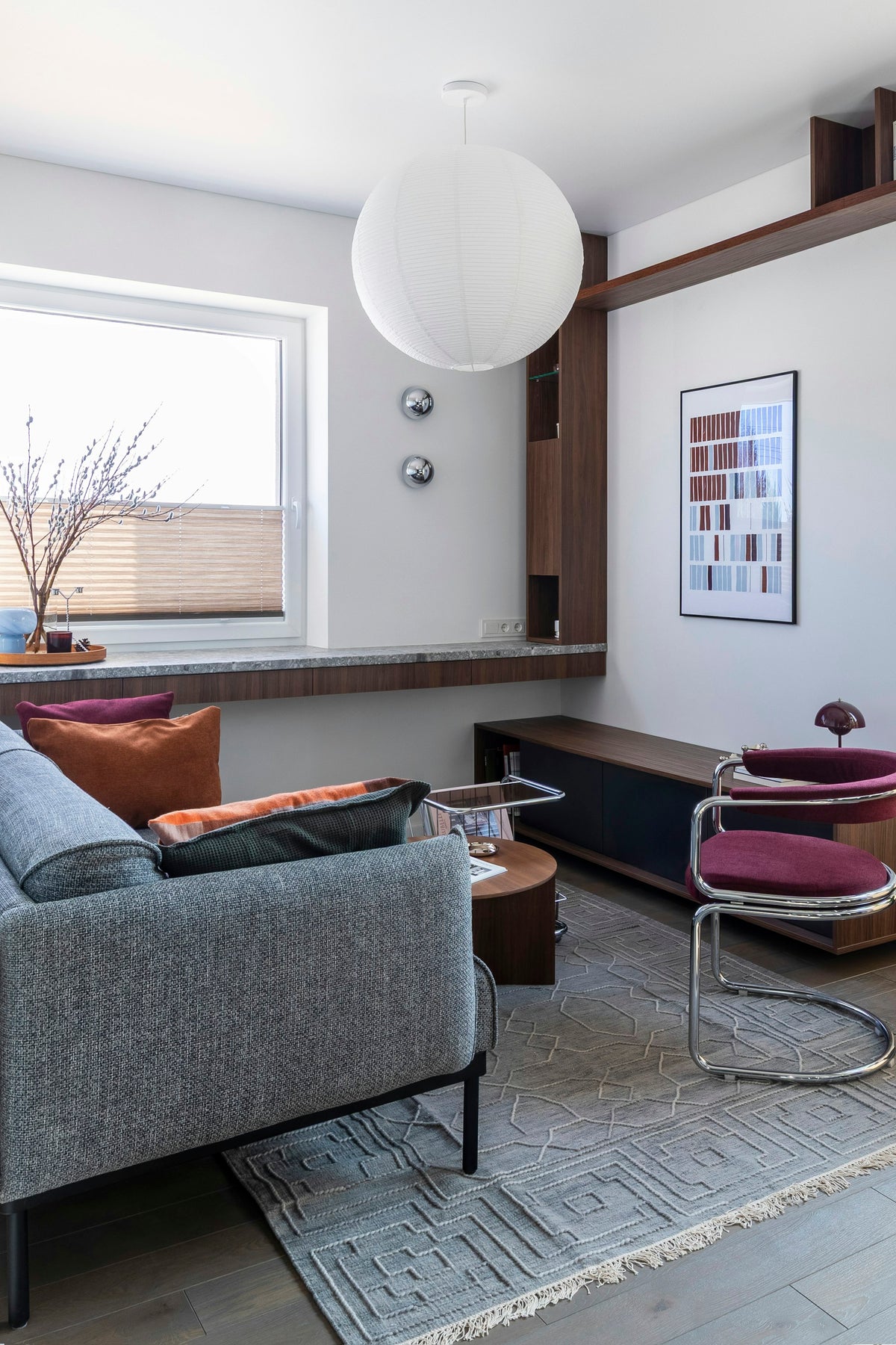 Compact, bright living room with grey sofa, paper pendant light, built-in shelving and chrome chair